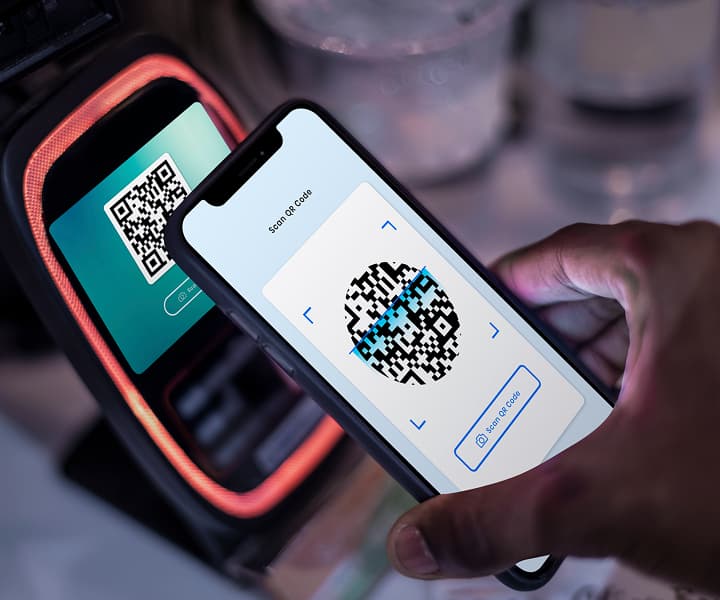 Hand holding a phone near a contactless payment terminal