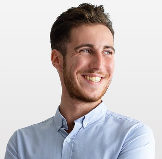 Smiling man in a blue shirt, short haircut, brown-haired with a beard
