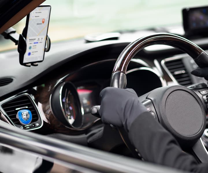 Driver's seat: hands on the steering wheel, phone attached to the left side of the windshield with an open app